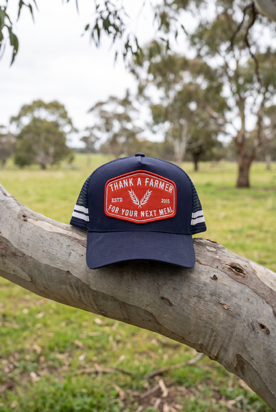 Navy stripe trucker cap with red Thank A Farmer patch on gum branch
