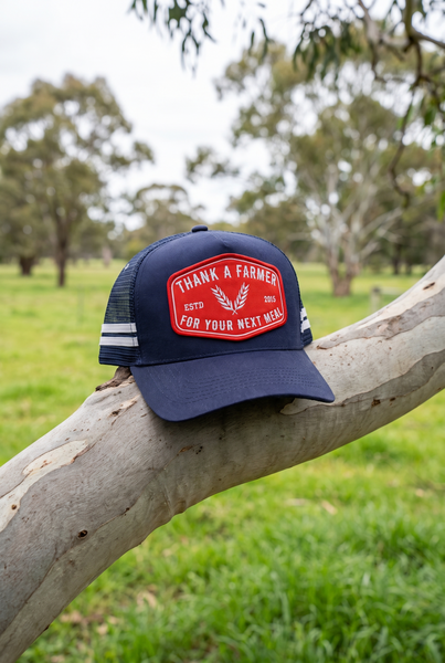 Navy stripe trucker cap with red Thank A Farmer patch, angled view