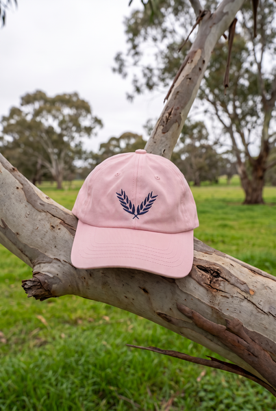 Pink dad cap with navy wheat emblem on gum branch