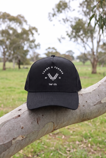 Black trucker cap with white wheat TAF Co embroidery on gum branch